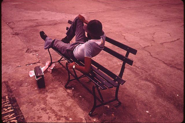 Original caption: "Man Lounging on a Park Bench with His Radio on the Reis Park Boardwalk in New York City. 07/1974"